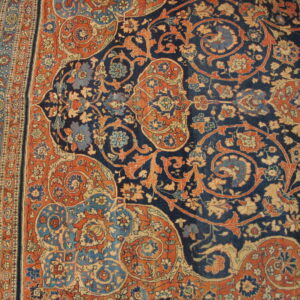 Detailed navy rug with dense orange and blue floral motifs and an elaborate multicolored striped border.