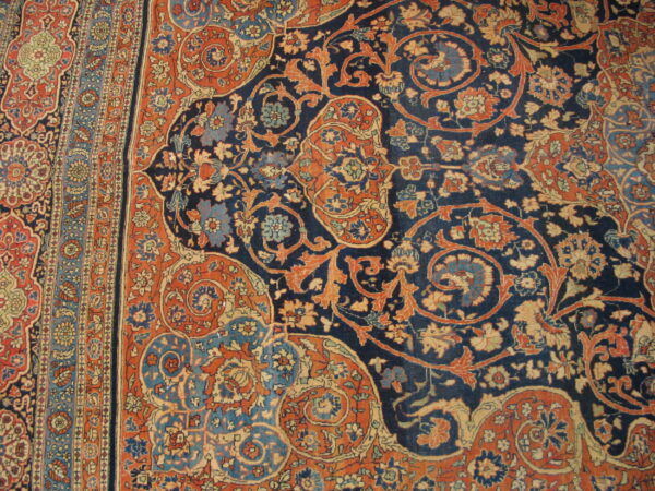 Detailed navy rug with dense orange and blue floral motifs and an elaborate multicolored striped border.