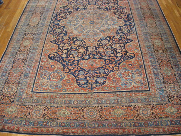 Traditional low-pile rug with complex floral patterns in deep blue, rust, and light blue on hardwood.