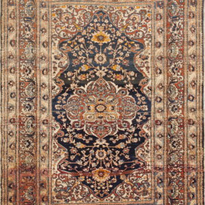 A detailed traditional rug featuring a navy blue medallion field and wide borders in beige and rust.