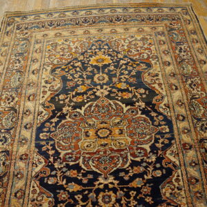 Intricate floral medallion rug in navy, gold, and terracotta colors rests on distressed wooden planks.