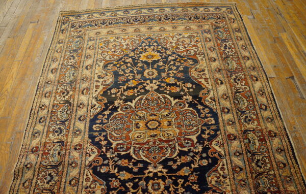 Intricate floral medallion rug in navy, gold, and terracotta colors rests on distressed wooden planks.