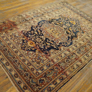 Traditional patterned rug in navy, cream, and rust colors on distressed light brown wooden floorboards.