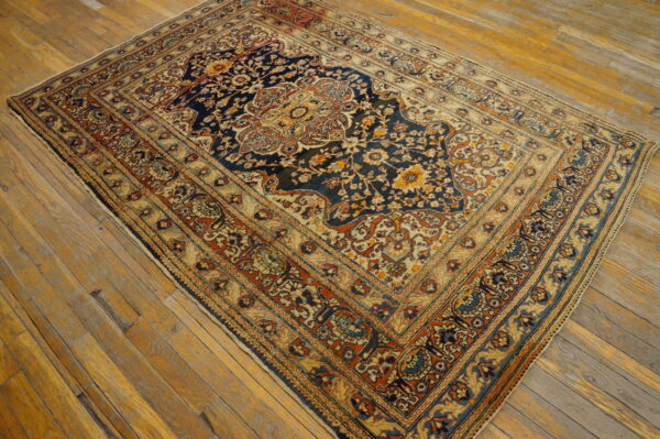 Traditional navy and beige low-pile rug with floral medallion sits on rustic golden-toned hardwood flooring.