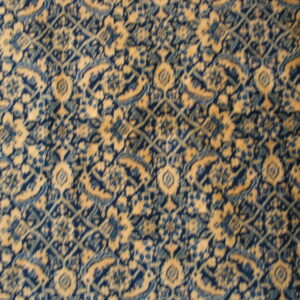 Muted blue and gold rug featuring an intricate, repeating medallion and trellis design.