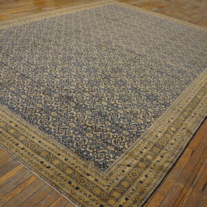 Traditional blue and beige rug with a dense pattern laid over distressed plank flooring.