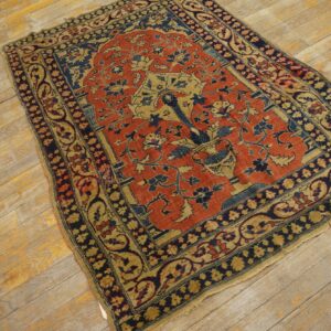 A traditional red, navy, and gold rug with a tree-of-life pattern sits on distressed wooden planks.