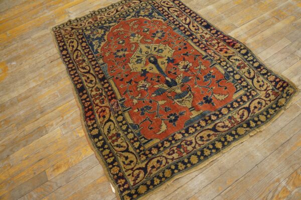 A traditional red, navy, and gold rug with a tree-of-life pattern sits on distressed wooden planks.
