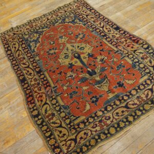 Red, gold, and dark blue antique-style rug featuring a floral vase medallion on worn wood flooring.