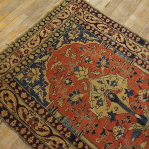 Ornate red, dark blue, and beige low-pile rug lying diagonally on light distressed wood planks.