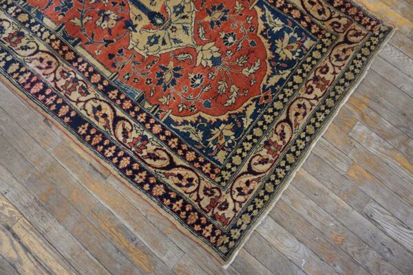 Close-up of a traditional red, navy, and tan floral rug corner on rustic gray wood planks.