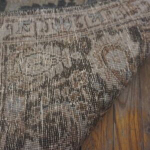 Distressed brown and tan patterned rug with light blue details rests on rustic wood planks.