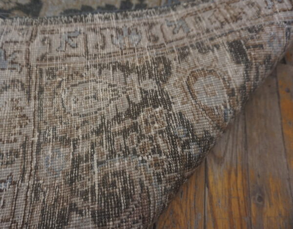 Distressed brown and tan patterned rug with light blue details rests on rustic wood planks.