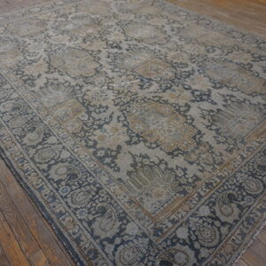Distressed traditional rug in muted indigo, gray, and beige on rustic wood plank flooring.