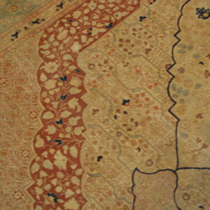 Ornate traditional rug detail showing beige, rust red, and blue floral motifs within curving borders.