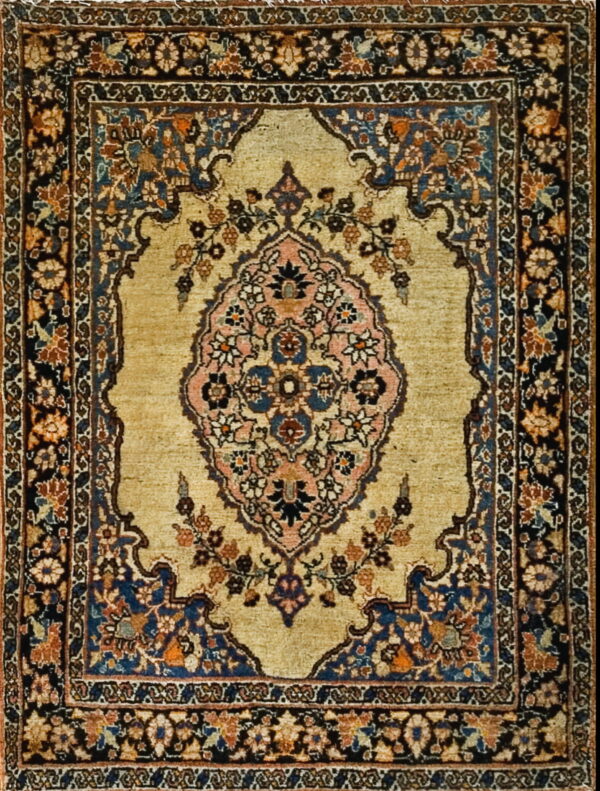 Traditional rug with a gold field, a pink and blue medallion, and dark navy floral borders.