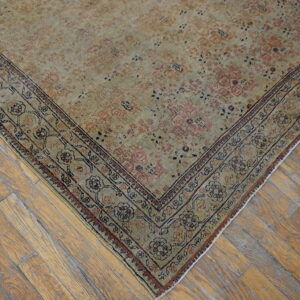 Distressed beige and muted pink traditional rug rests diagonally on wide-plank wood flooring.