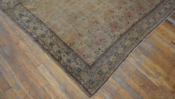 Distressed beige and muted pink traditional rug rests diagonally on wide-plank wood flooring.
