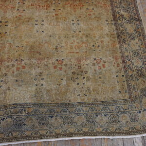 Distressed tan and gold rug featuring faded navy and rust patterns rests on rustic gray wood planks.