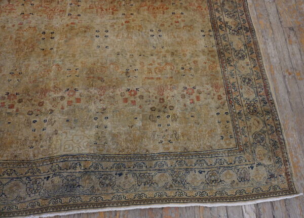 Distressed tan and gold rug featuring faded navy and rust patterns rests on rustic gray wood planks.