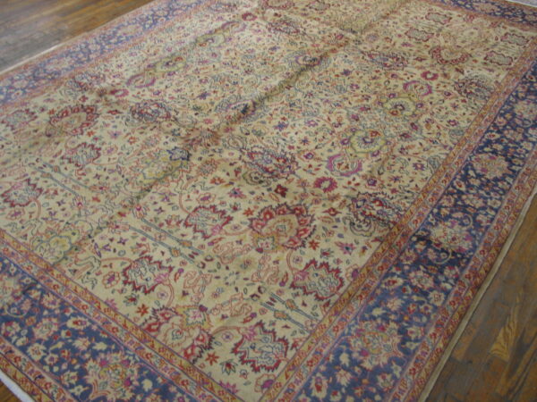 Ornate low-pile rug featuring a cream field with colorful floral motifs and wide navy blue borders.