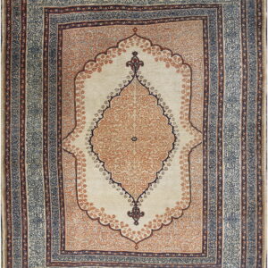 Traditional style cream rug featuring a dense orange floral medallion and dark blue patterned borders.