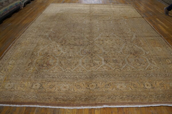 Monochromatic large tan rug displaying an intricate trellis pattern against a glossy wood plank floor.
