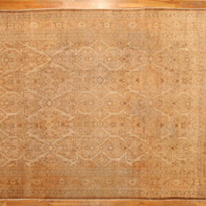 Tonal gold and tan rug with intricate geometric and floral patterns lies on light brown hardwood flooring.