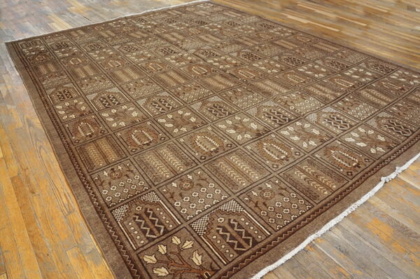 Monochromatic brown rug featuring a geometric repeating grid and stylized floral designs on distressed wood floors.