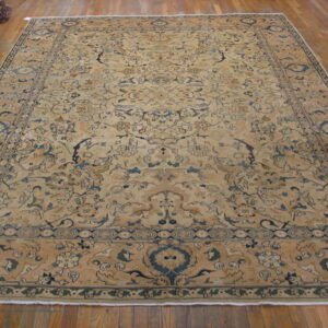 Large beige traditional rug with intricate blue floral patterns laid flat on a hardwood floor.