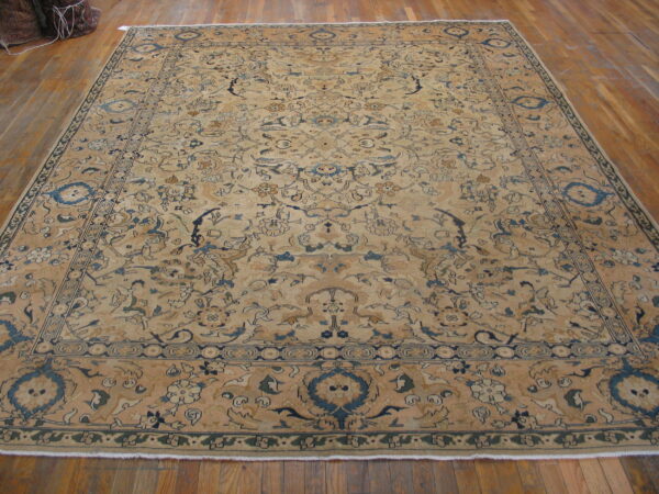 Large beige traditional rug with intricate blue floral patterns laid flat on a hardwood floor.