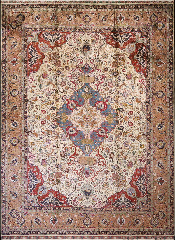 Intricate patterned rug with an ivory field, large blue medallion, red corners, and a wide sienna border.