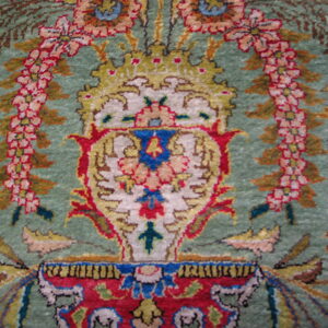 Ornate rug detail showing a red, gold, and cream central design against a sage green field.