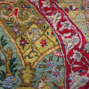 Ornate rug detail in red, olive, and teal sits on a wooden plank floor.