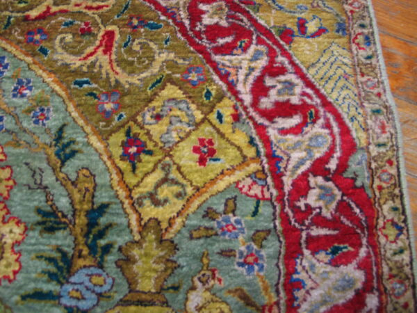 Rare green color fine luxurious silk pile antique persian tabriz islamic prayer design rug 5 Ornate rug detail in red, olive, and teal sits on a wooden plank floor.