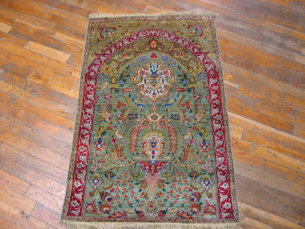 Rare green color fine luxurious silk pile antique persian tabriz islamic prayer design rug 8 Ornate low-pile rug with green and red floral mihrab pattern displayed on light wood floor.