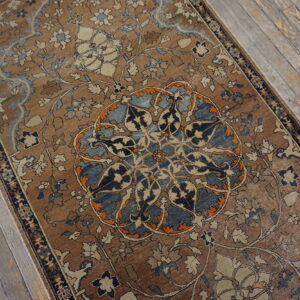Brown rug featuring complex blue, cream, and orange floral patterns resting on weathered wood flooring.