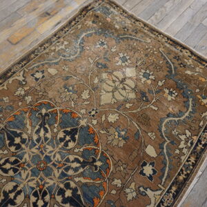 Low-pile floral rug in brown, blue, and cream colors lying on light gray wood planks.