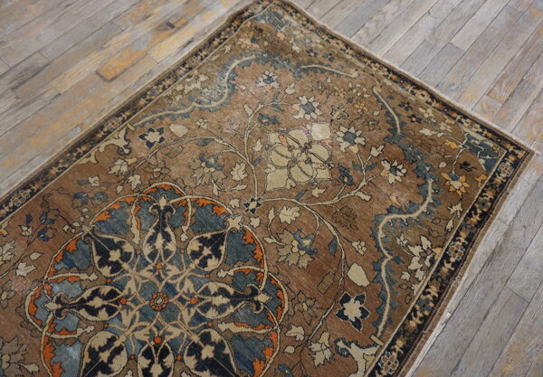 Low-pile floral rug in brown, blue, and cream colors lying on light gray wood planks.