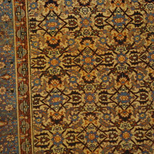 Low-pile rug detail showing gold, blue, and rust geometric and floral patterns next to wood flooring.