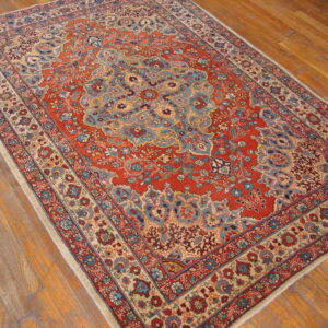 Ornate red, blue, and cream floral rug with a central medallion on a glossy wood floor.