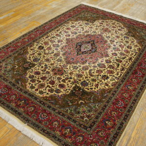 Ornate traditional rug featuring an ivory field, pink medallion, and red border on yellow wooden flooring.