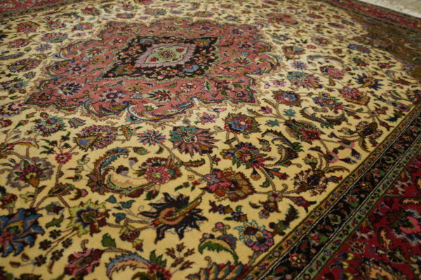 Traditional rug featuring a central rose medallion and intricate multicolored floral details on a cream field.