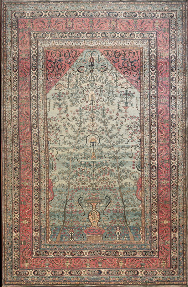 Ornate rug featuring a pale blue-green tree of life design beneath a decorated arch, framed by salmon borders.