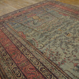 Muted teal rug with a detailed floral pattern and multi-layered terracotta and blue-black borders on wood floor.