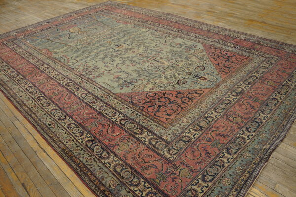 Ornate traditional rug with a light blue central field and complex dusty rose borders on plank flooring.