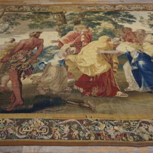 Large tapestry-style rug displaying a figural scene with rich colors and an ornate floral border.