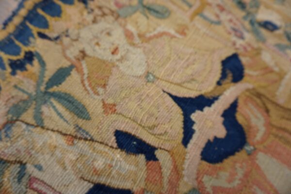 Detailed close-up of a low-pile rug featuring figural and floral patterns in blue, pink, and pale yellow.