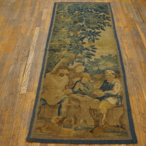 A long, low-pile rug featuring a muted blue and tan figurative scene is laid upon rustic wood planks.