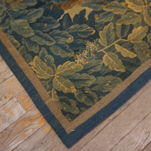 Low-pile botanical rug in deep teal and green lies on rustic wood plank flooring.